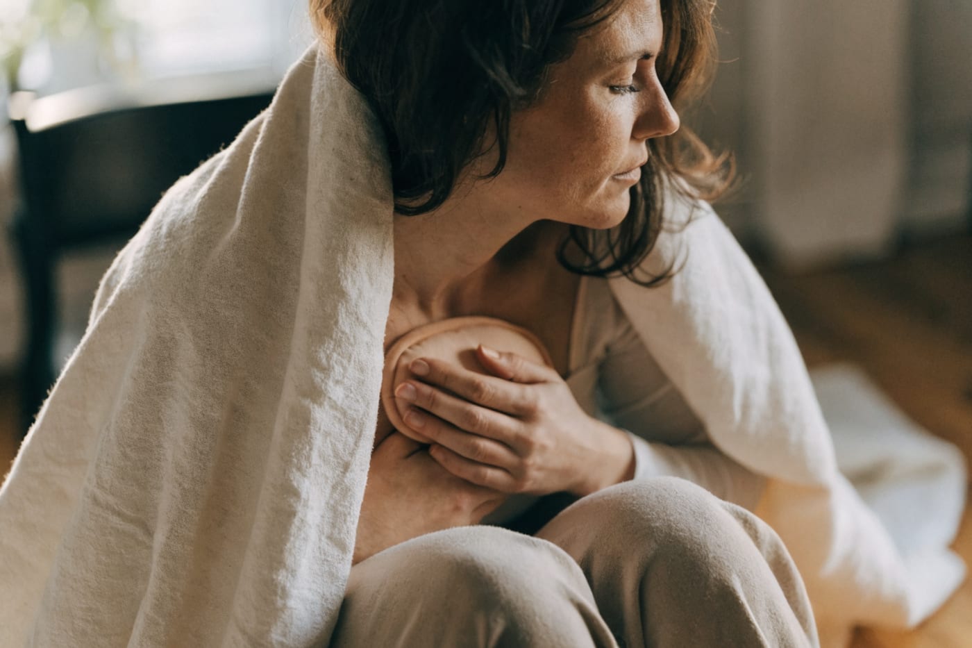 madre abrigándose las manos y el pecho con una manta después de amamantar